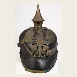 Casque à pointe prussien de troupe d'infanterie de ligne, Première Guerre mondiale, vu de face : cuir noir, aigle de laiton au chiffre FR, pointe sur base ronde à quatre rivets, visière bordée de métal