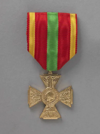 Croix du combattant volontaire 1939-1945 en bronze : branches ornées de feuilles de laurier, poilu casqué de profil au centre sur un glaive pointé vers le haut, ruban rouge à bande centrale verte et bordures jaunes