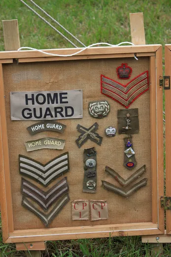 Panneau de jute d'un exposant présentant des insignes de tissu, chevrons de grade et badges de la Home Guard britannique lors d'un salon