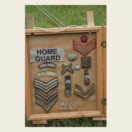 Panneau de jute d'un exposant présentant des insignes de tissu, chevrons de grade et badges de la Home Guard britannique lors d'un salon