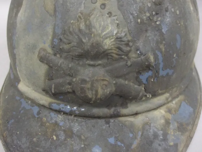 Gros plan de l'attribut de l'artillerie sur un casque Adrian de la Grande Guerre